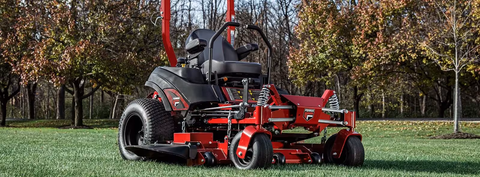 Ferris zero-turn mower cutting a manicured lawn with autumn trees behind