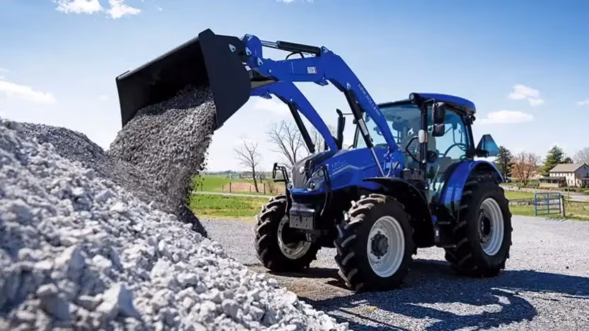 New Holland utility tractor loading gravel with a front loader
