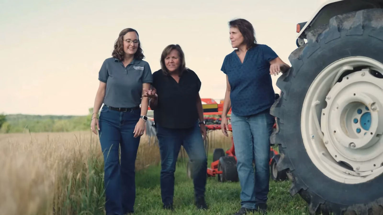Three of the office team beside a tractor
